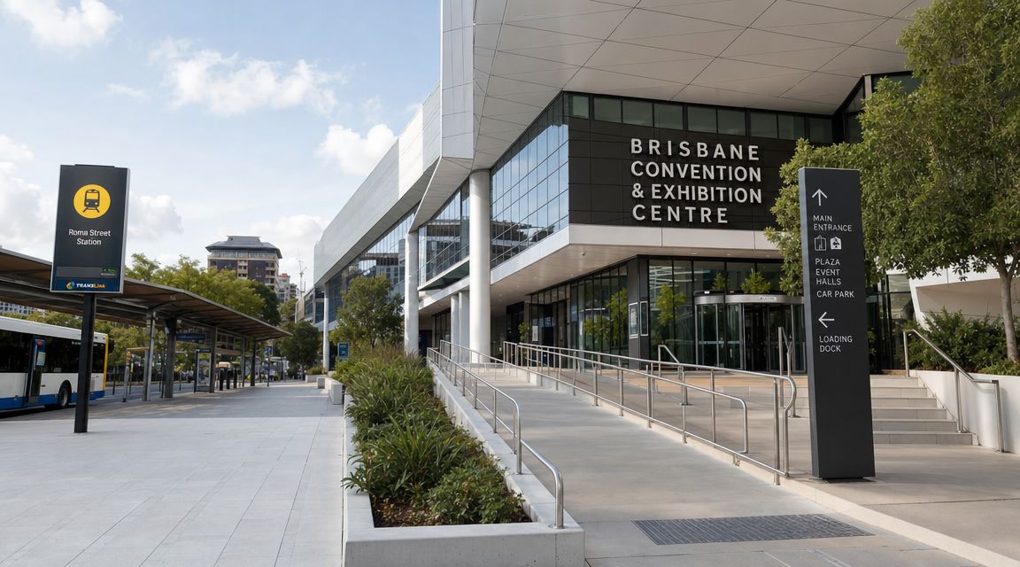 A modern building exterior of the Brisbane Convention and Exhibition Centre with a nearby bus station sign.