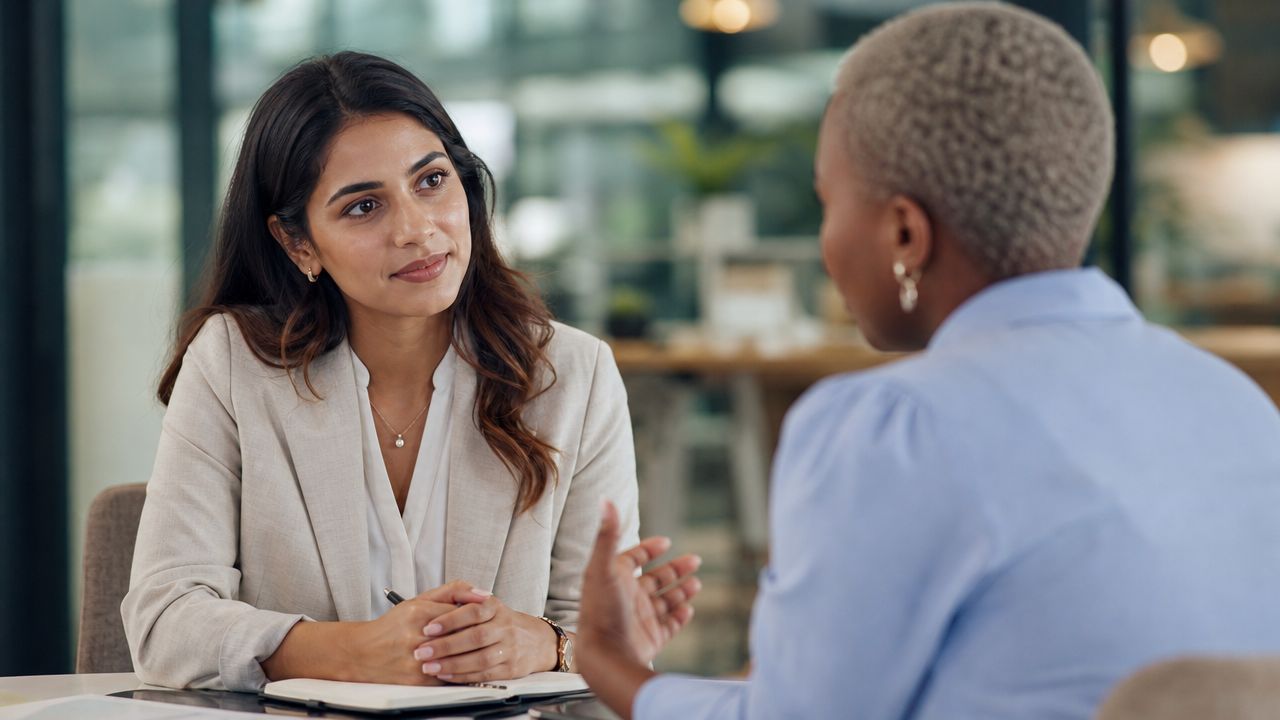 Two professional women having a productive business discussion and making eye contact in a modern office.