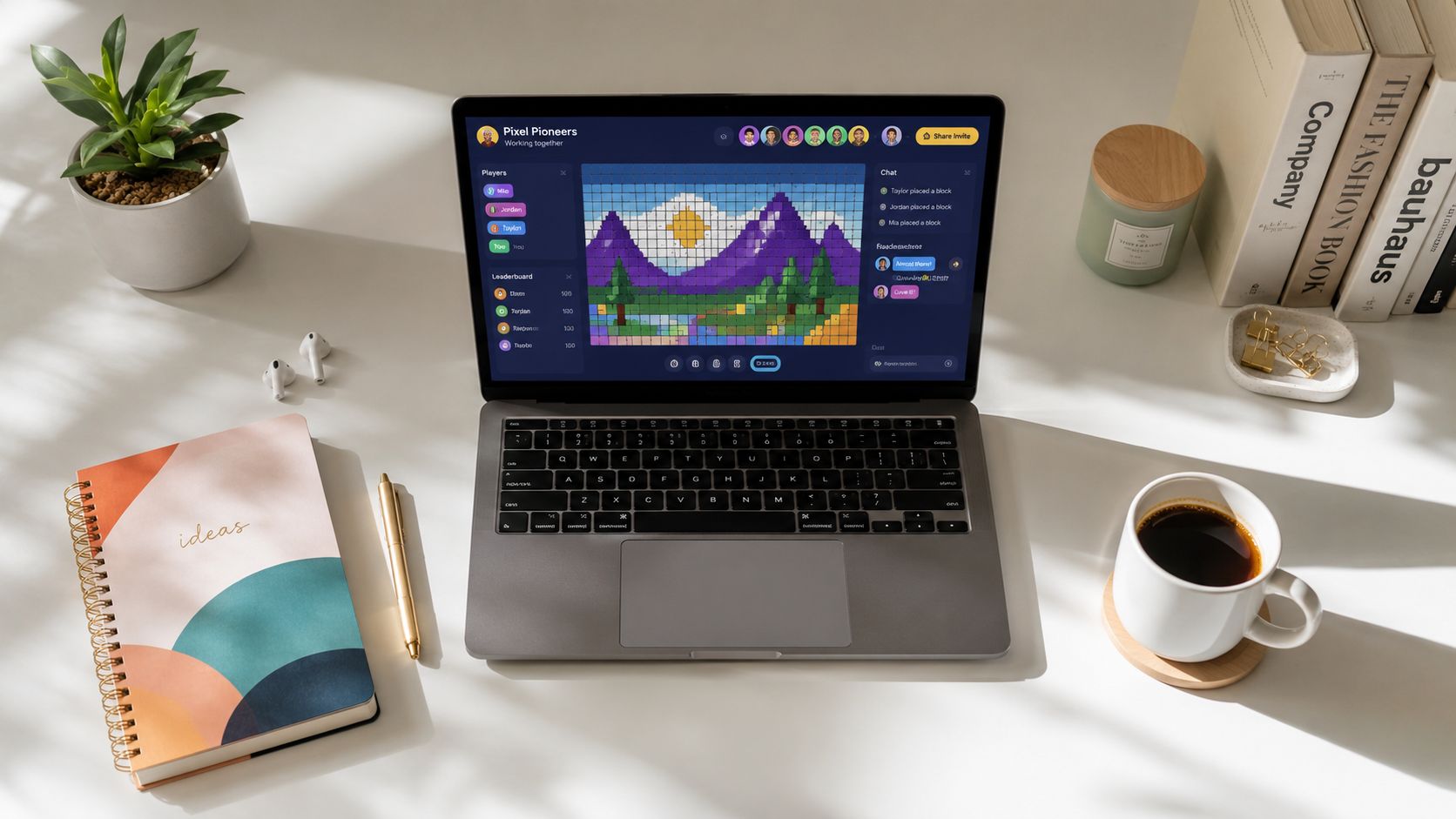 A modern desk with a laptop displaying a pixel art collaboration tool, notebook, coffee, and office supplies.
