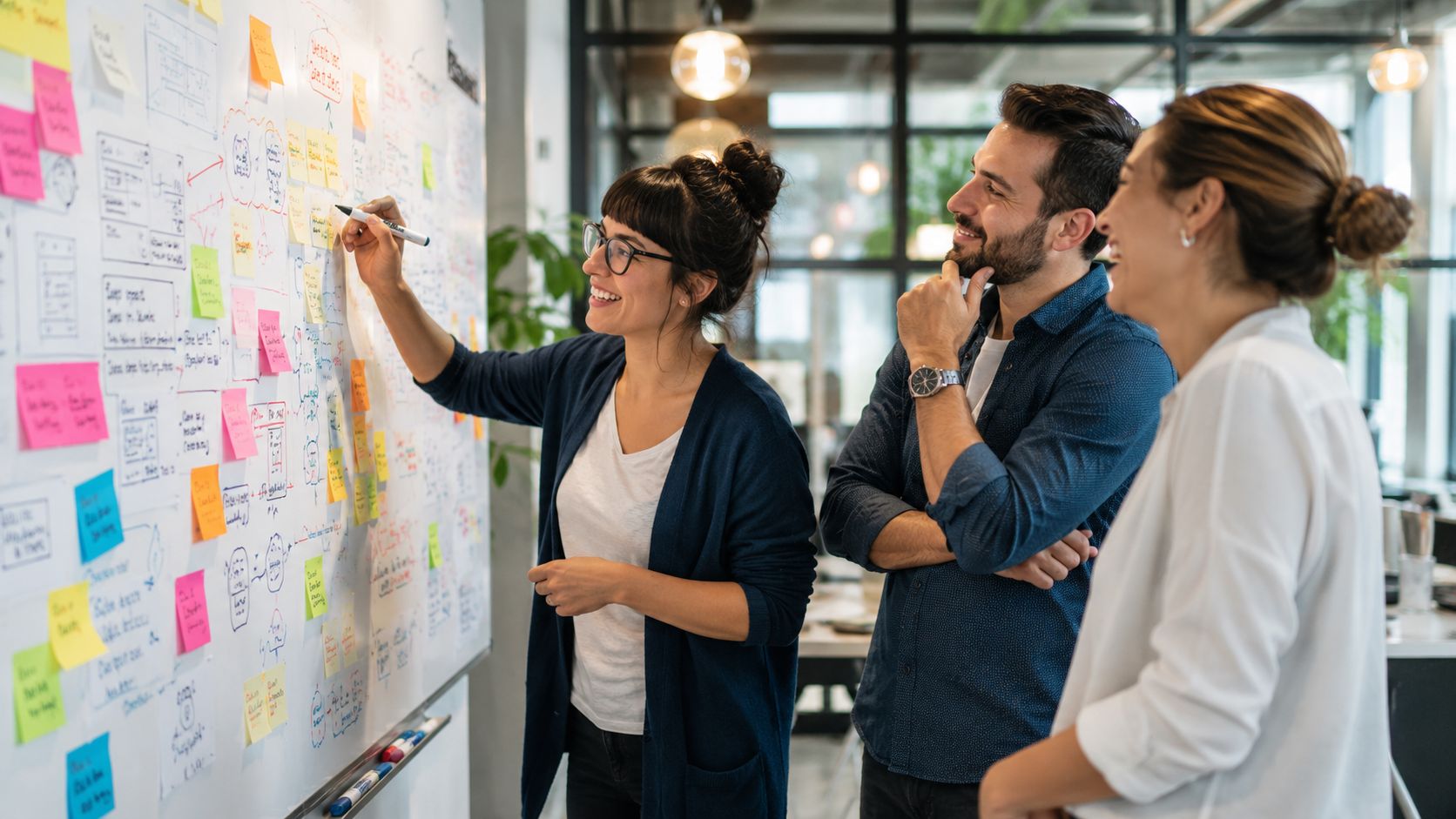 A diverse team collaborating in a modern office while brainstorming on a whiteboard filled with sticky notes.